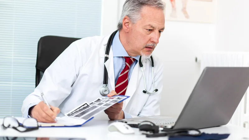 Médico PJ analisando documentos fiscais com calculadora e notebook, representando a complexidade do ISS e a necessidade de planejamento tributário.