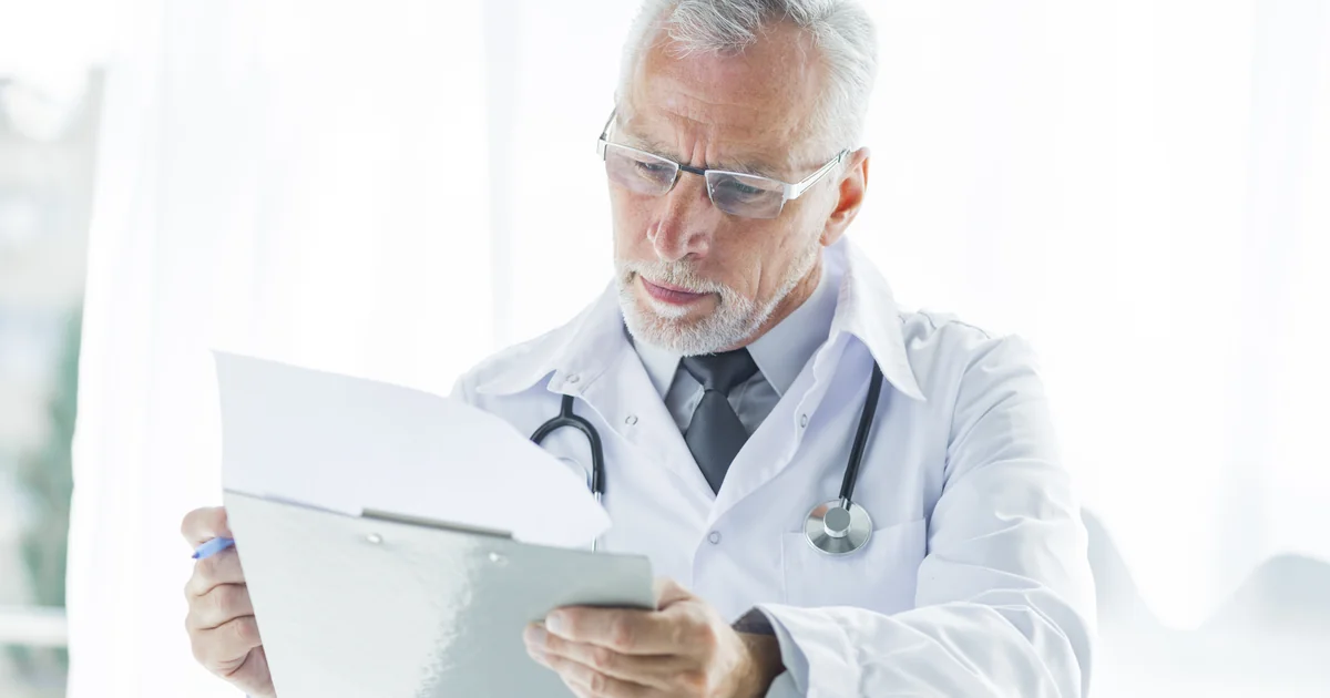 Médico analisando documentos tributários no consultório
