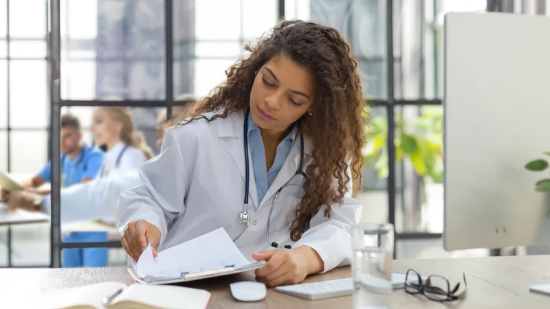 Médico ou dentista organizando notas fiscais eletrônicas em um tablet, com documentos e gráficos ao fundo, simbolizando a gestão fiscal de uma clínica.